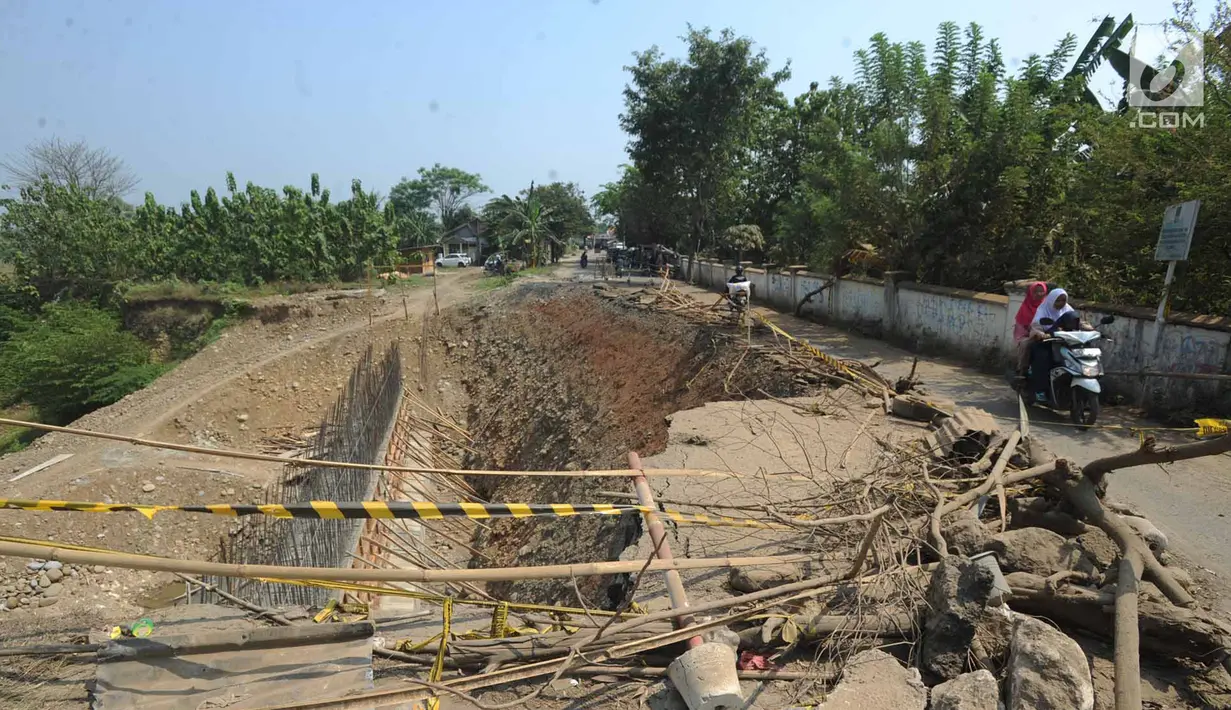 Suasana jalan longsornya tepian jembatan Cipamingkis Cibarusah, Kab Bekasi, Jawa Barat (15/7). Walaupun saat ini sedang dilakukan proses perbaikan longsor namun dikeluhkan warga karena berjalan lamban. (Merdeka.com/Arie Basuki)