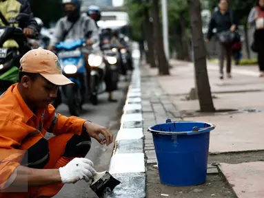 Petugas dari Kelurahan Karet Semanggi mengecat trotoar di kawasan Jalan Semanggi, Jakarta, Selasa (1/3/2016). Trotoar itu dipercantik dengan dicat ulang oleh Petugas Prasarana Sarana Umum (PPSU). (Liputan6.com/Faizal Fanani)