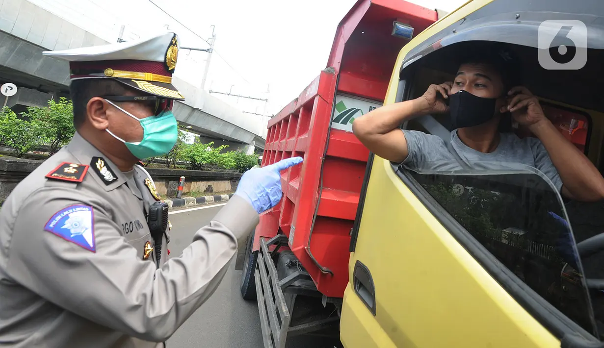 Petugas menyuruh pengemudi truk mengenakan masker saat kegiatan Check Point Pengawasan Pelaksaanaan PSPBB di Jakarta selatan, Jumat (10/4/2020). Kegiatan gabungan Dishub dan Polda Metro Jaya menyasar pengemudi kendaraan bermotor yang tidak menggunakan masker. (merdeka.com/Arie Basuki)