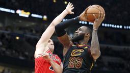 Pebasket Cleveland Cavaliers, LeBron James, dihadang pebasket Chicago Bulls, Paul Zipser, pada laga NBA di United Center, Selasa (5/12/2017). Cleveland Cavaliers menang 113-91 atas Chicago Bulls. (AP/Charles Rex Arbogast)