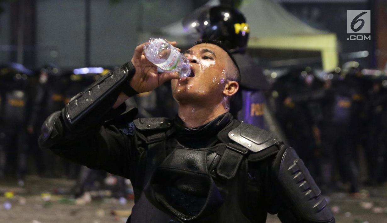 Personil Kepolisian dari satuan Brimob beristirahat di sela-sela menghalau massa yang berlaku anarkis di sekitar depan Gedung Bawaslu, Jalan MH Thamrin, Jakarta, Rabu (22/5/2019). Aksi unjuk rasa yang dimotori  GNKR berakhir ricuh. (Liputan6.com/HelmiFithriansyah)