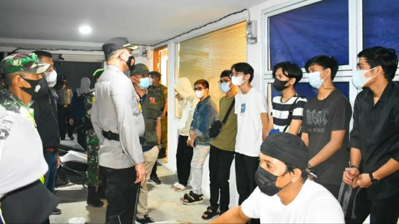 Petugas memberikan peringatan kepada warga yang masih berkerumun melewati jam malam.
