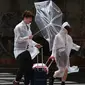 Pasangan berjalan melawan angin kencang saat hujan di dekat stasiun Osaka, (4/9). Pelayanan kereta lokal berencana menghentikan semua layanan kereta cepat &lsquo;shinkansen&rsquo; di tiga kota Osaka, Tokyo, dan Hiroshima. (AFP Photo/Jiji Press)