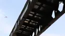 Sebuah pesawat terlihat di atas Jembatan Penyeberangan Orang (JPO) Pasar Minggu yang akan segera diturunkan di Jakarta, Kamis (4/4). Dampak dari proses penurunan JPO yang ambruk beberapa tahun lalu tersebut adalah pengalihan arus lalu lintas di sekitar lokasi. (Liputan6.com/Immanuel Antonius)
