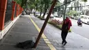 Pejalan kaki melintas di dekat tiang yang miring di Jalan Gedung Kesenian, Jakarta, Jumat (22/2). Keberadaan tiang miring tersebut membahayakan keselamatan pejalan kaki karena kabel yang turut menjuntai hingga ke bawah. (Liputan6.com/Immanuel Antonius)