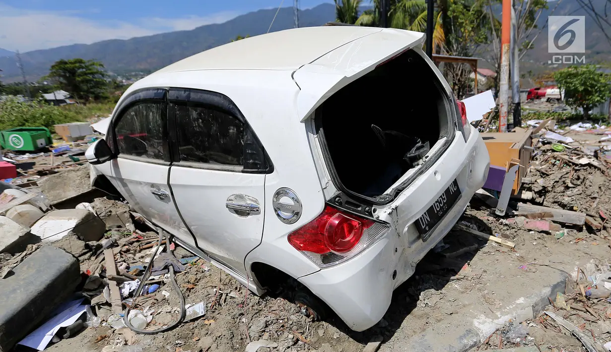 Sebuah mobil Honda Brio menjadi incaran jarahan korban gempa dan tsunami di Palu Grand Mal, Palu, Jumat (5/10). Warga korban gempa bumi mengambil ban dan interior mobil. (Liputan6.com/Fery Pradolo)