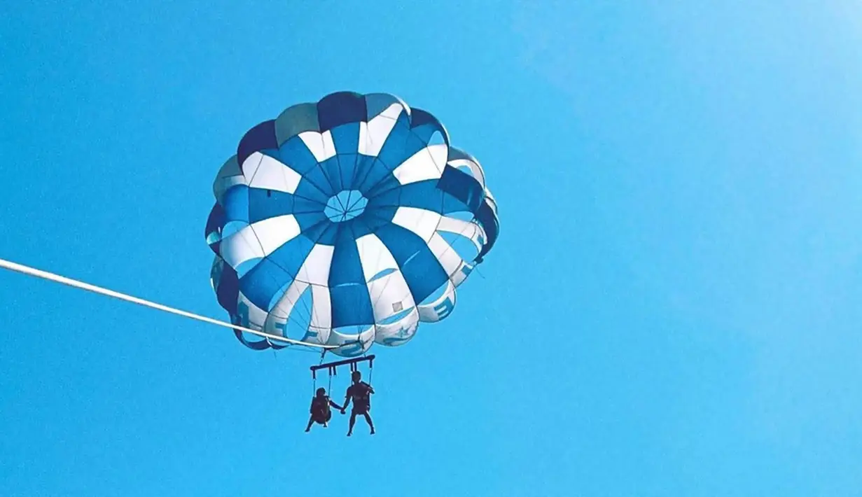 Usai dari Jogja, Alca dan Bintang Emon menikmati serunya bulan madu di Bali. Dalam liburannya ini keduanya banyak menikmati wisata air hingga parasailing. Seru menikmati indahnya pemandangan dari ketinggian sambil ditarik oleh kapal, momen ini tentu memacu adrenalin. (Liputan6.com/IG/@bintangemon)