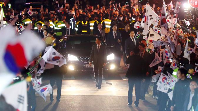 Ratusan pendukung mengibarkan bendera nasional menyambut mantan Presiden Korsel, Park Geun-hye di rumah pribadinya di Seoul, Minggu (12/3). Park Geun-hye meninggalkan Blue House setelah resmi dimakzulkan Mahkamah Konstitusi (MK) Korsel. (str/YONHAP/AFP)