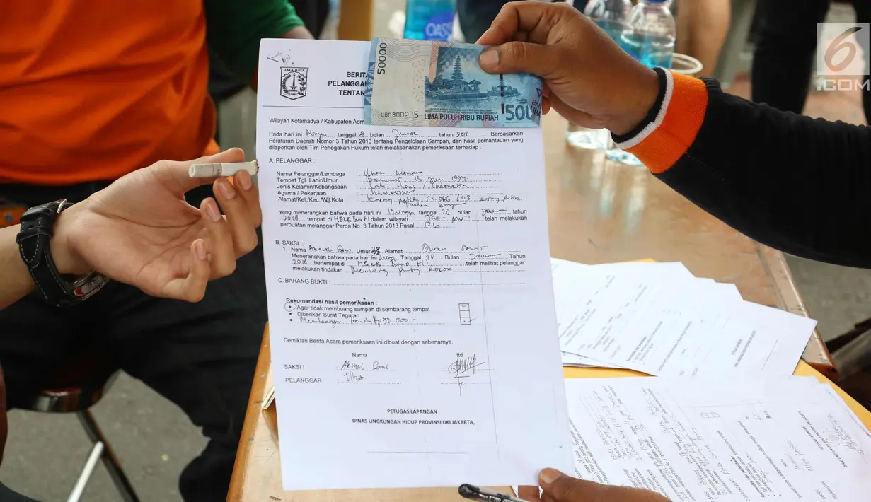Petugas menunjukkan surat berita dan uang denda pelanggaran membuang sampah saat CFD di Jakarta, Minggu (28/1). Petugas juga memberi hukuman sosial atau denda minimal Rp 100.000. (Liputan6.com/Angga Yuniar)