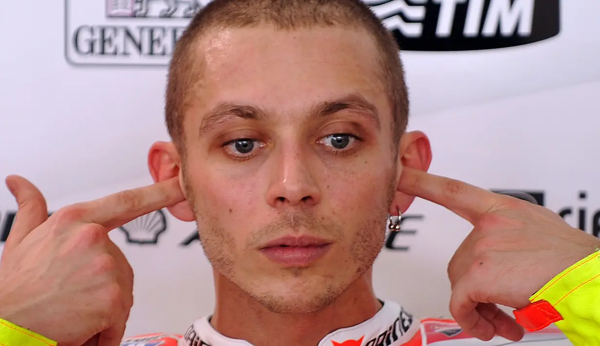 Pebalap MotoGP asal Italia, Valentino Rossi menutup kupingnya saat balapan di Sirkuit Sepang, Malaysia, Senin (1/2/2011). (AFP/Saeed Khan)