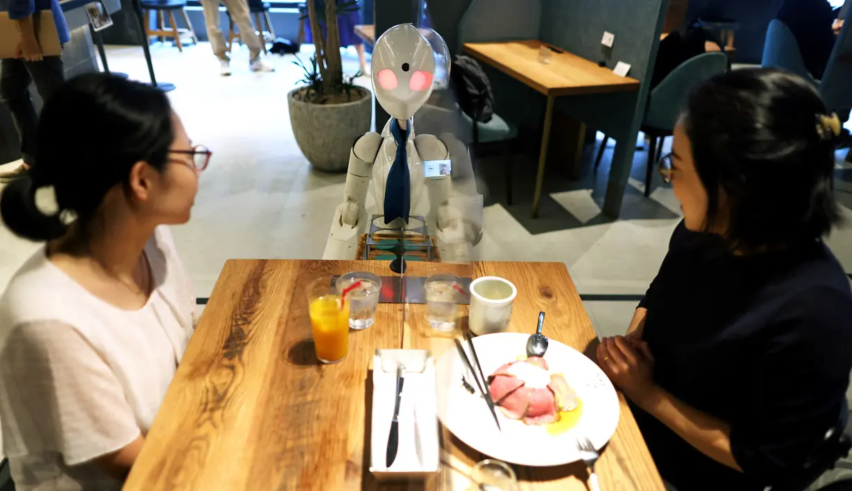 Robot humanoid mengantarkan minuman kepada pelanggan di Dawn Cafe, Tokyo, Jepang, 17 Agustus 2021. Peluncuran kafe ini bersamaan dengan Paralimpiade yang akan dibuka pada 24 Agustus. (Behrouz MEHRI/AFP)