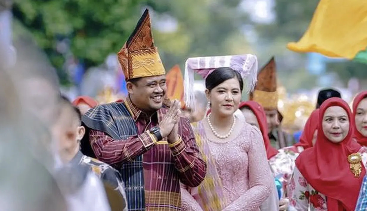 Sandal berhak warna merah dengan detail dua tali silang tipis dengan hiasan bunga mini dikenakan oleh Kahiyang.  Perempuan 32 tahun ini memoles wajahnya dengan  makeup tidak berlebihan dan mengenakan lipstik peach yang membuat tampilannya lebih fresh.  (@ayanggkahiyang)