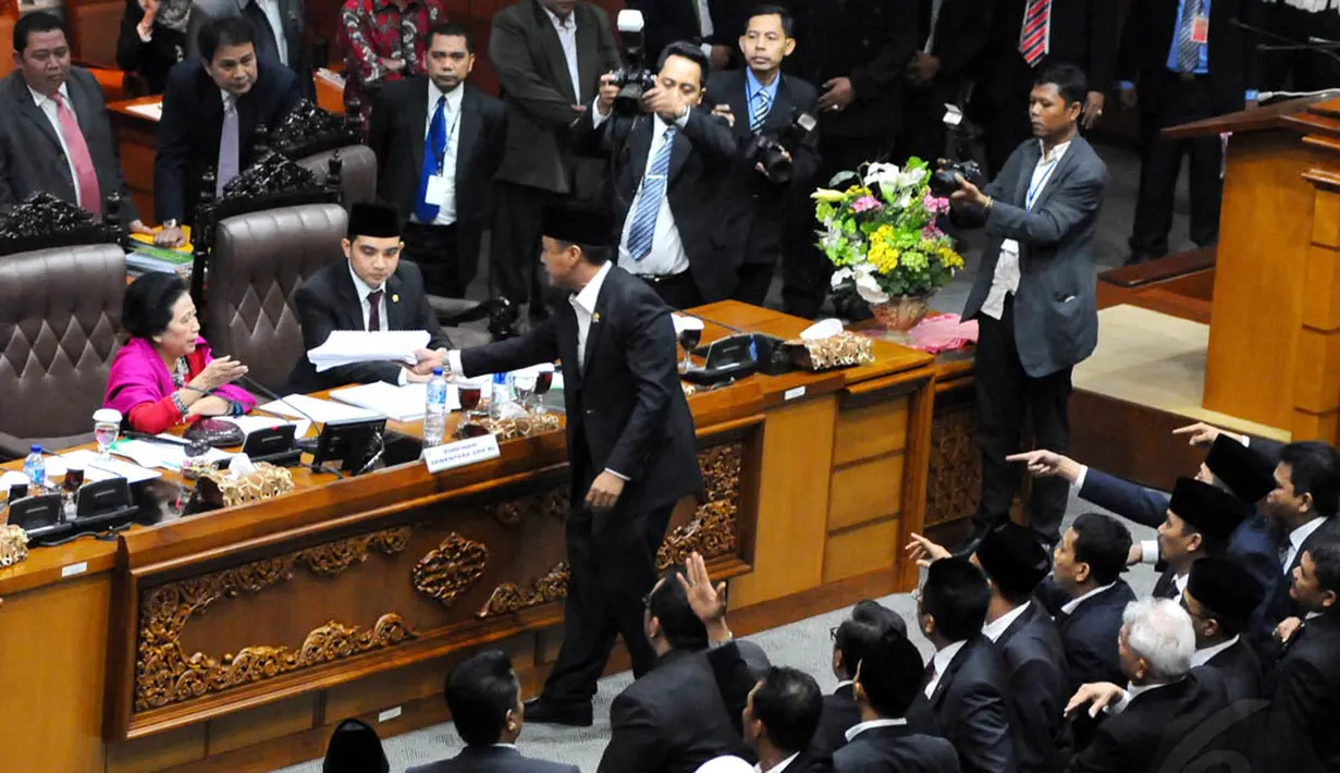 Seorang anggota DPR RI meletakan berkas di meja Popong Otce Djundjunan karena tidak puas dengan sikap Ketua DPR RI sementara tersebut, Jakarta, (1/10/14). (Liputan6.com/Andrian M Tunay)