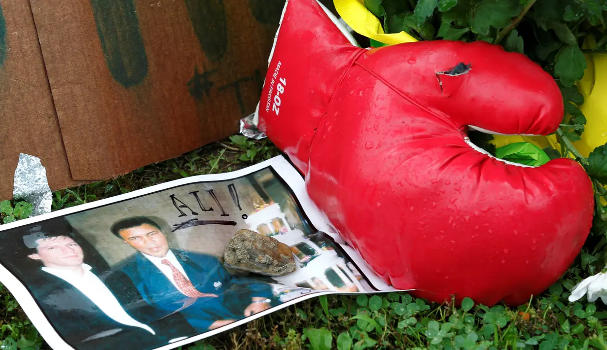 Sebuah foto dan sarung tinju diletakkan di rumah masa kecil Muhammad Ali untuk memberi penghormatan terakhir bagi petinju legendaris tersebut, di Louisville, Kentucky, AS, Sabtu (4/6). Muhammad Ali meninggal pada usai 74 tahun. (REUTERS/John Sommers II)
