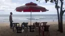 Seorang pedagang menata kursi saat menunggu pelanggan di Pantai Kuta, Bali, Kamis (14/10/2021). Pemerintah mulai membuka penerbangan internasional ke Bali bagi 19 wisatawan mancanegara mulai hari ini. (AP Photo/Firdia Lisnawati)
