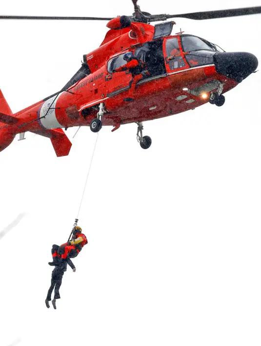 Penyelam Penjaga Pantai AS yang ditambatkan pada helikopter menarik tubuh pengendara mobil yang terjebak dalam arus deras di tepi Air Terjun Niagara, New York, AS, 8 Desember 2021. Wanita itu tidak bergerak ketika pihak berwenang tiba di tempat kejadian. (Sharon Cantillon/The Buffalo News via AP)