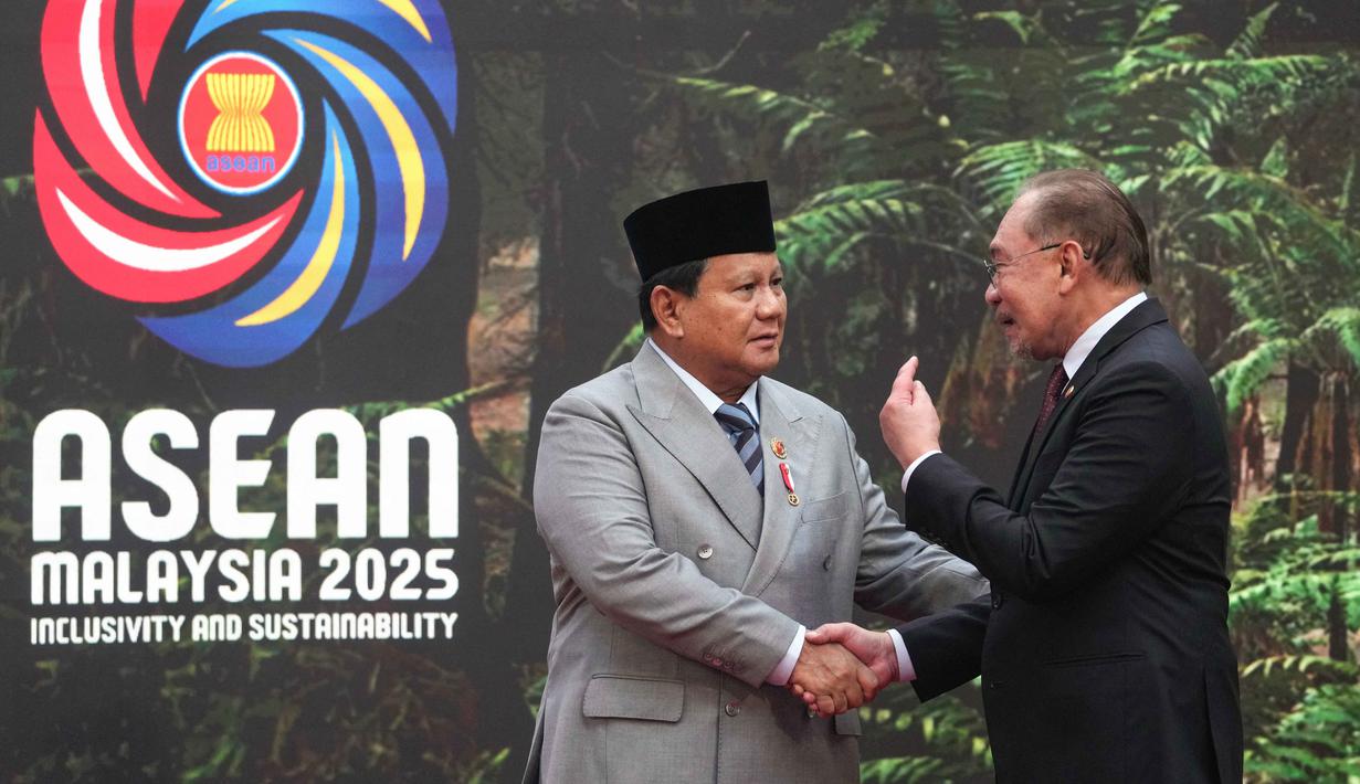 Presiden Republik Indonesia, Prabowo Subianto (kiri) disambut Perdana Menteri Malaysia Anwar Ibrahim saat tiba untuk menghadiri Konferensi Tingkat Tinggi (KTT) ke-47 negara-negara Asia Tenggara (ASEAN) di Kuala Lumpur pada 26 Oktober 2025. (Rafiq Maqbool/POOL/AFP)