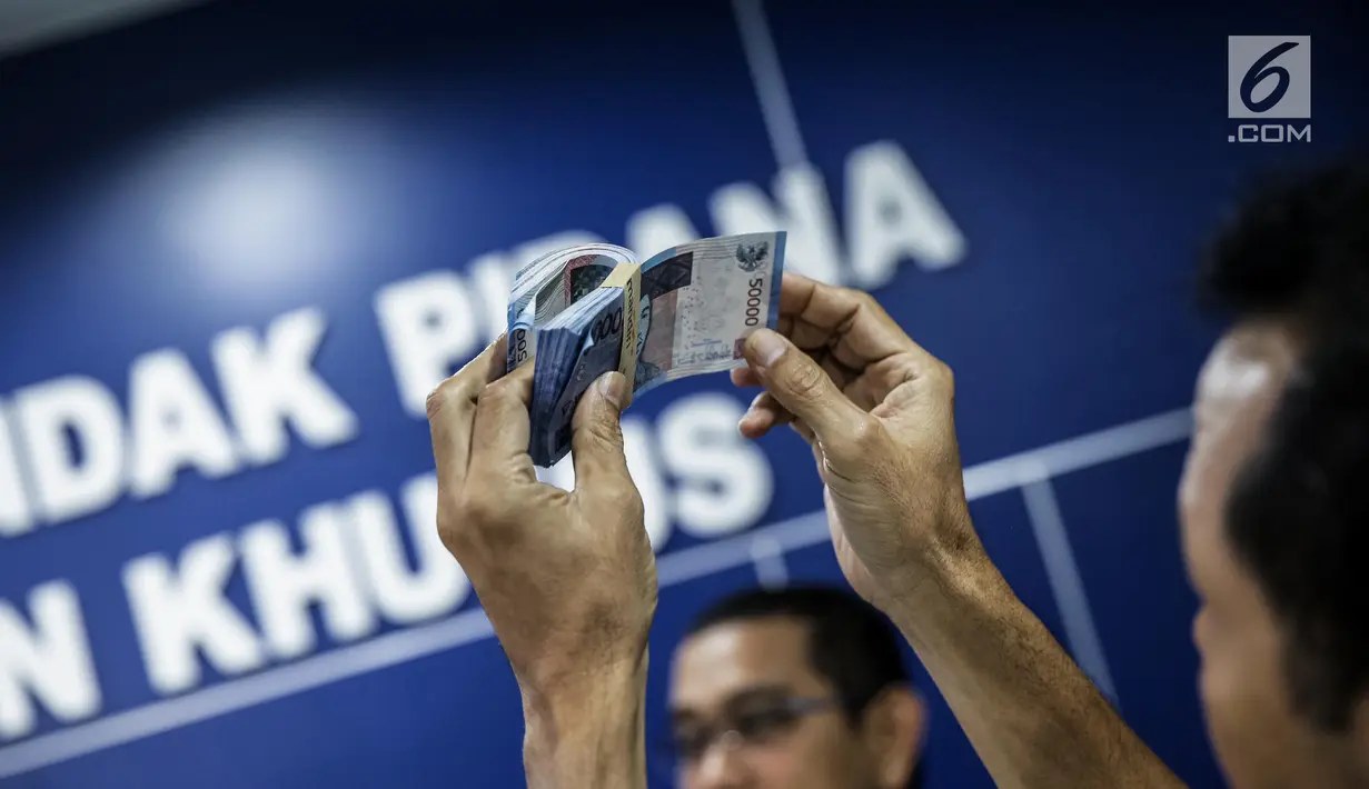 Petugas Direktorat Tindak Pidana Ekonomi Khusus Bareskrim Polri memperlihatkan uang palsu saat rilis di Bareskrim Polri, Jakarta, Jumat (16/6). Sejumlah alat pembuat uang, seperti printer, laminating, dan komputer diamankan. (Liputan6.com/Faizal Fanani)