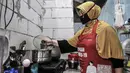 Siti Zahro (44) mengenakan celemek berbahan tas bansos Covid-19 buatannya di industri jahit rumahan KG-Lupe Fashion, Salemba, Jakarta, Senin (16/11/2020). Inovasi Siti bermula dari sepinya pesanan jahit akibat pandemi. (merdeka.com/Iqbal S. Nugroho)