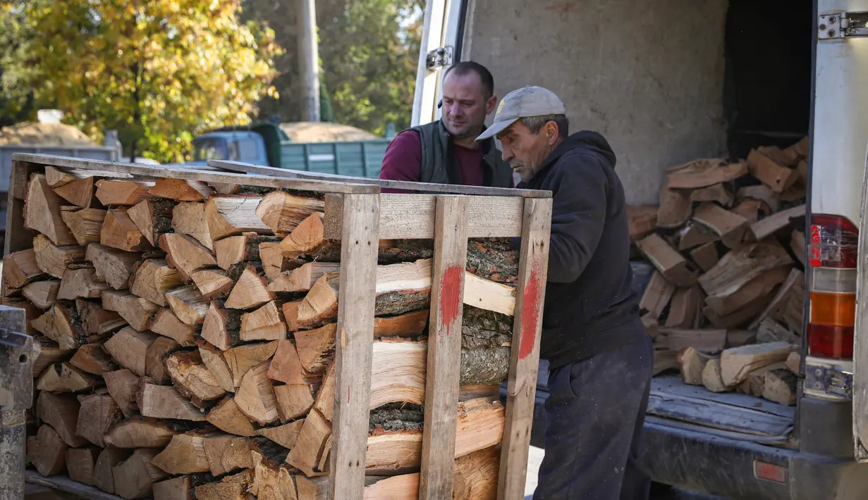 Orang-orang memuat kayu bakar dari palet ke dalam mobil van di luar Chisinau, Moldova, 15 Oktober 2022. Krisis energi yang melanda Eropa karena dipicu pemotongan aliran gas alam oleh Rusia di tengah perangnya melawan Ukraina telah memaksa beberapa orang untuk beralih ke kayu bakar untuk menghangatkan diri dalam cuaca yang beranjak dingin. (AP Photo/Aurel Obreja)