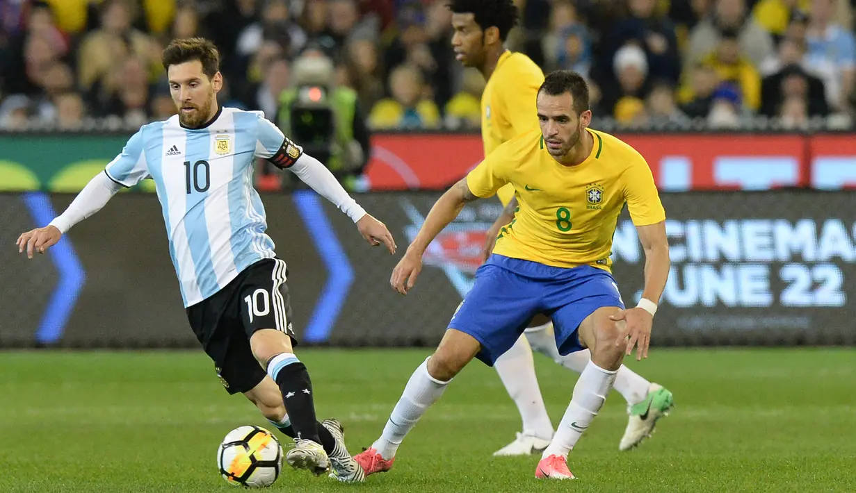 Penyerang Argentina, Lionel Messi (kiri) berusaha mengiring bola dari kawalan gelandang Brasil, Renato Augusto pada laga persahabatan di MCG di Melbourne (9/6). Argentina menang atas Brasil dengan skor 1-0. (AFP Photo/Mal Fairclough)