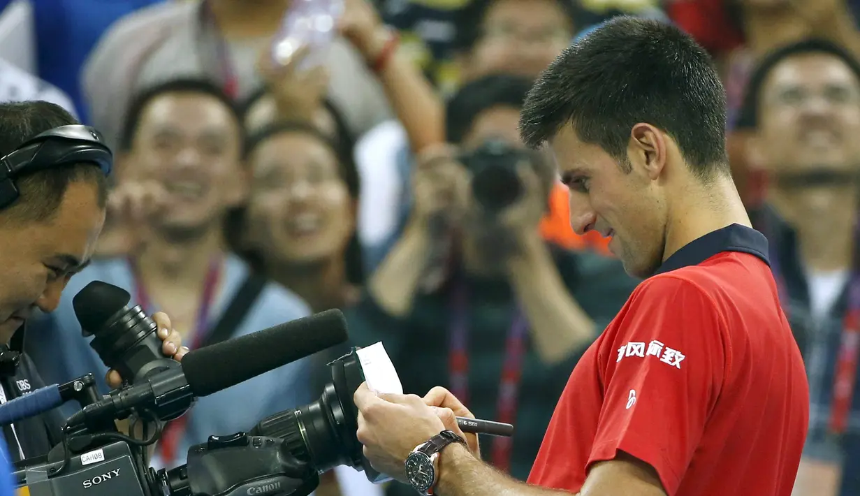 Petenis  Novak Djokovic melakukan tanda tangan di kamera usai menang atas petenis Italia Simone Bolelli di China Open tennis tournament, Beijing, China, Selasa (06/10/2015).  (REUTERS/Kim Kyung-Hoon)