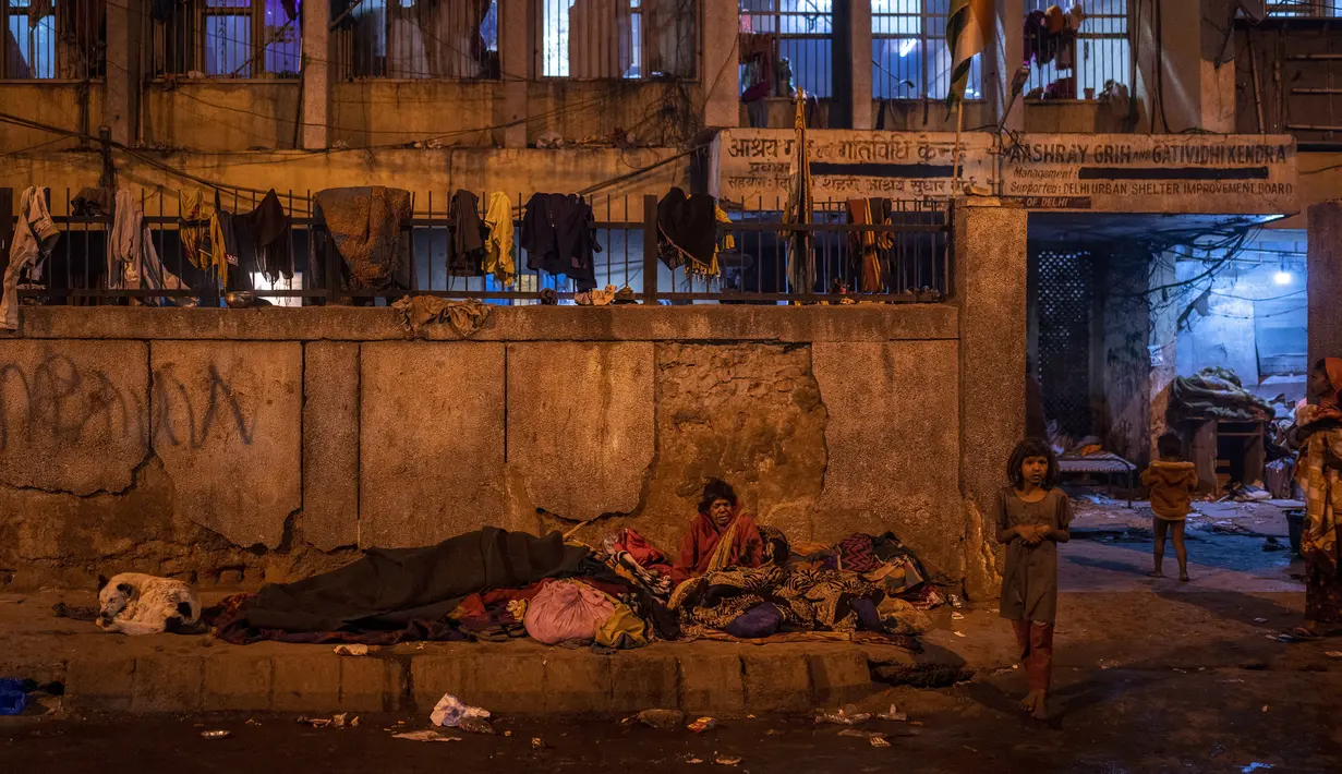 Seorang perempuan tua tinggal di trotoar di luar tempat penampungan bobrok untuk para tunawisma pada malam musim dingin di New Delhi, 28 Desember 2022. 195 tempat penampungan tunawisma di New Delhi hanya dapat menampung sekitar 19.000 orang, membuat puluhan ribu orang berjuang untuk tetap hangat. (AP Photo/Altaf Qadri)