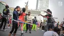 Anak-anak bermain permainan tradisional hula hoop ditemani sejumlah mahasiswa dari Penggerak Olahraga saat car free day (CFD) di kawasan Bundaran HI, Jakarta, Minggu (14/7/2019). Kegiatan yang rutin digelar ini bertujuan mengajak masyarakat DKI Jakarta aktif berolahraga. (Liputan6.com/Faizal Fanani)