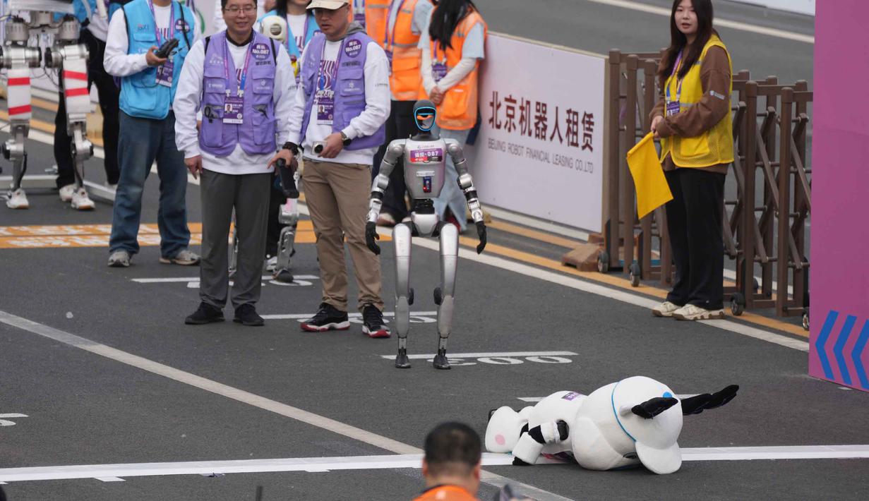 Terdapat dua kategori utama, yaitu navigasi otonom (robot bergerak sendiri tanpa kendali jarak jauh) dan kendali jarak jauh. Tampak dalam foto, sebuah robot terjatuh di garis start Beijing E-Town Half Marathon dan Humanoid Half Marathon yang diadakan di pinggiran Beijing pada Minggu 19 April 2026. (AP Photo/Ng Han Guan)