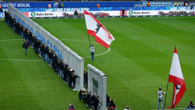 Para penggemar mengambil bagian dalam pertunjukan replika Tembok Berlin pada hari peringatan 30 tahun runtuhnya Tembok Berlin sebelum pertandingan Hertha Berlin melawan RB Leipzig di Stadion Olimpiade, Berlin (9/11/2019). (AFP/Odd Andersen)