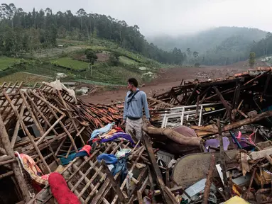 Seorang pria berdiri di dekat reruntuhan rumah saat tim penyelamat mencari korban yang terkubur longsor di Desa Pasirlangu, Cisarua, Kabupaten Bandung, Jawa Barat, pada 26 Januari 2026. Hari ini Selasa 27 Januari 2026, operasi pencarian dan pertolongan korban longsor di Desa Pasirlangu, Cisarua, Kabupaten Bandung, Jawa Barat, kembali dilanjutkan. (Aditya Aji/AFP)