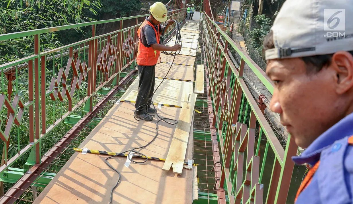 Pekerja menyelesaikan pembangunan jembatan gantung yang diberi julukan Indiana Jones di Srengseng Sawah, Jagakarsa, Jakarta, Jumat (3/8). Pemprov DKI membangun jembatan Indiana Jones karena yang lama sudah tidak layak. (Liputan6.com/Immanuel Antonius)