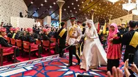 Pangeran Abdul Mateen dan Yang Mulia Anisha Rosnah berjalan menyusuri pelaminan saat resepsi pernikahan mereka di Istana Nurul Iman di ibu kota Brunei, Bandar Seri Begawan pada 14 Januari 2024. (Iqbal Selamat / AFP)
