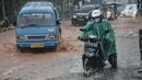 Pengendara mendorong sepeda motor saat melintasi genangan lumpur di Jalan Raya Sawangan, Depok, Minggu (7/11/2021). Hujan deras yang mengguyur Depok dan sekitarnya menyebabkan Jalan Raya Sawangan  digenangi banjir lumpur dan membahyakan keselamatan pengendara. (merdeka.com/Iqbal S Nugroho)