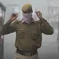 Polisi India menutup wajahnya dengan saputangan saat melewati jalan di New Delhi yang diselimuti kabut asap akibat polusi udara, Rabu (8/11). Organisasi Kesehatan Dunia menempatkan New Delhi sebagai kota paling berpolusi di dunia. (SAJJAD HUSSAIN/AFP)