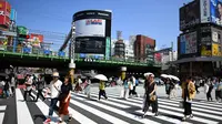 Sejumlah orang menggunakan payung dan topi untuk melindungi dirinya dari sinar matahari selama gelombang panas saat melintasi jalan di distrik Shinjuku Tokyo, Minggu (4/8/2019). Setelah menyerang beberapa wilayah di Eropa, suhu tinggi juga terjadi di Jepang. (Charly TRIBALLEAU / AFP)