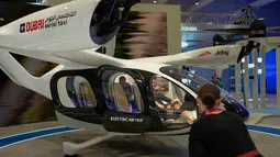 Dengan nomor registrasi N544JX, taksi udara listrik Joby melakukan penerbangan demonstrasi berawak selama Pameran Udara Dubai (Dubai Airshow) 2025. Tampak dalam foto, seorang wanita berfoto saat duduk di dalam taksi udara pada Pameran Udara Dubai, Uni Emirat Arab, Selasa 18 November 2025. (AP Photo/Altaf Qadri)