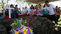 Keluarga korban bom gereja Surabaya menabur bunga pada pemakaman Martha Djumani di komplek Taman Makam Keputih, Surabaya, Rabu (16/5). Martha merupakan korban bom bunuh diri di Gereja Pantekosta Pusat Surabaya Minggu (13/5) lalu. (AP/Achmad Ibrahim)