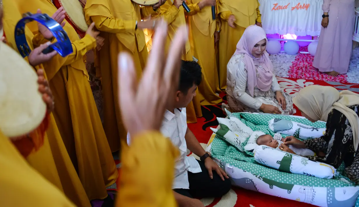 Seorang bayi menjalani ritual 'peutron tanoh aneuk' (turun tanah anak) di Banda Aceh, Aceh, Senin (15/7/2019). Ritual turun tanah anak telah menjadi tradisi sakral bagi masyarakat Aceh yang dilaksanakan pada saat bayi berusia 44 hari. (CHAIDEER MAHYUDDIN / AFP)
