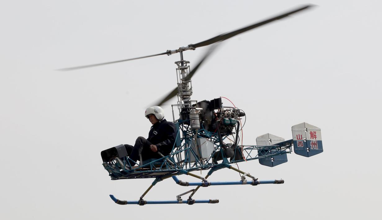 Pria 60 tahun bernama Guo Leiting saat terbang menggunakan helikopter buatannya sendiri di Yuncheng , provinsi Shanxi , Cina, 21 April 2016. Meskipun tinggal di desa dengan bahan seadanya, Ia mampu membuat helikopter. (REUTERS / Stringer)