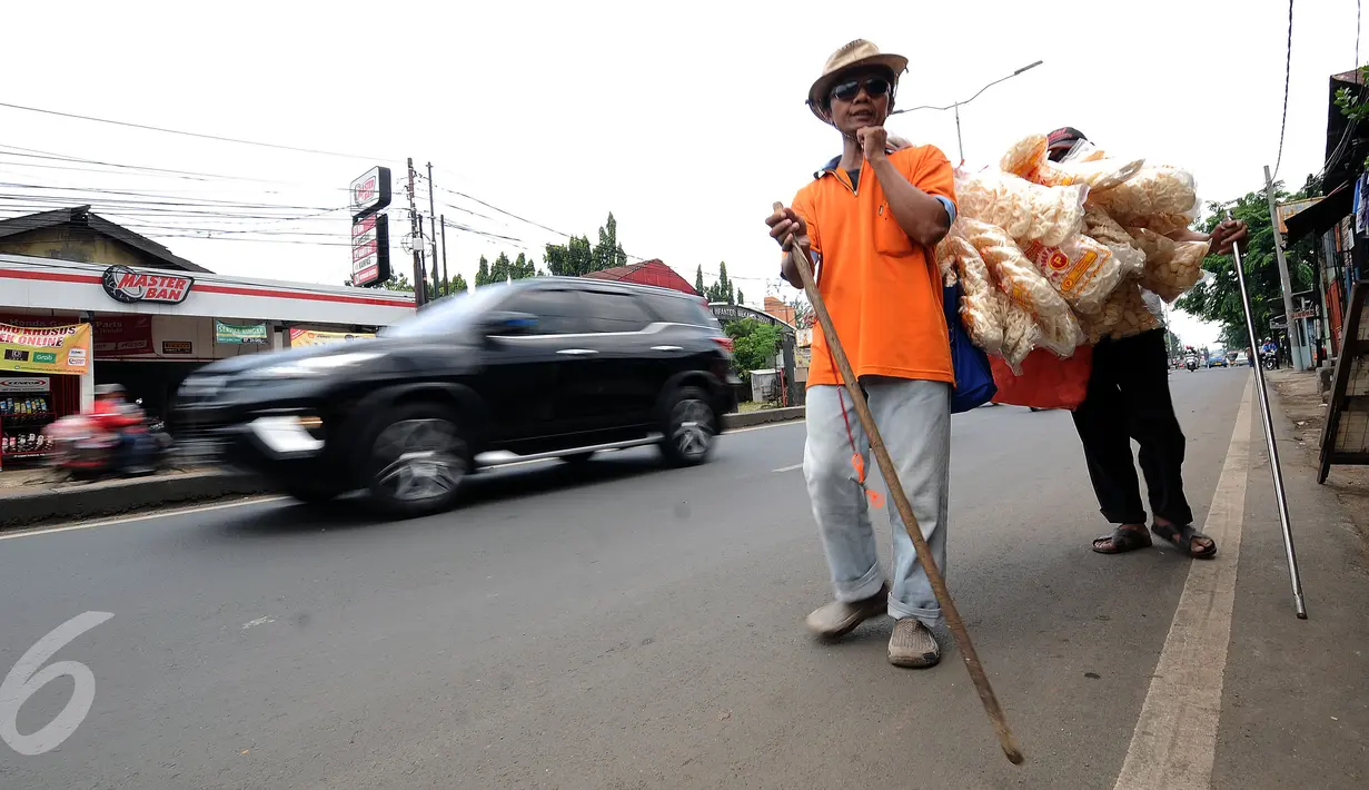 Iman (depan) bersama Drajat berjalan menjajakan kerupuk ikan di Jalan Raya Bogor, Depok, Jawa Barat, Rabu (19/10). Iman mengaku setiap harinya berjalan kaki dari kediaman di Jalan Akses UI hingga kawasan Cijantung. (Liputan6.com/Helmi Fithriansyah)