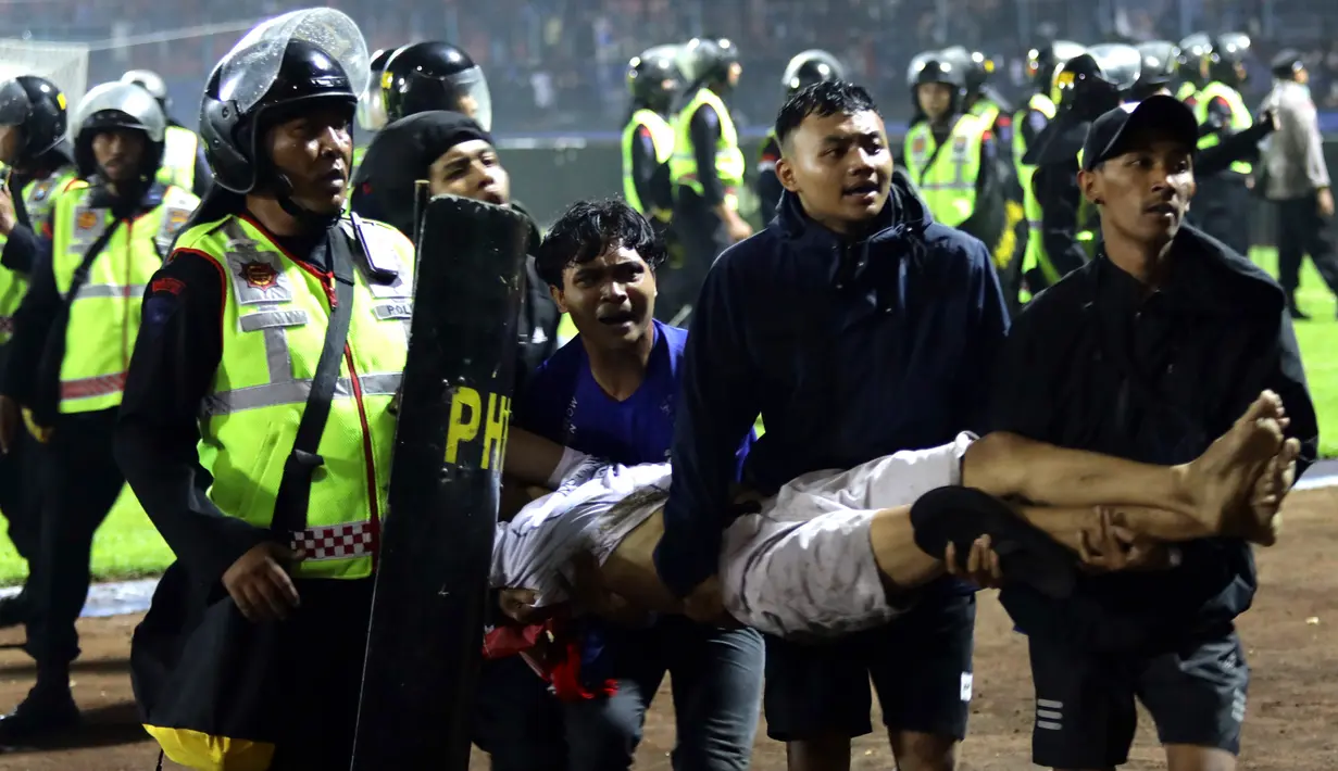 <p>Suporter membawa seorang pria yang terluka menyusul kerusuhan pada pertandingan sepak bola antara Arema Vs Persebaya di Stadion Kanjuruhan, Malang, Jawa Timur, 1 Oktober 2022. "Masih ada 180 orang yang masih dalam perawatan. Dari 40 ribu penonton, tidak semua anarkis. Hanya sebagian, sekitar 3.000 penonton turun ke lapangan," kata Kapolda Jawa Timur Irjen Pol Nico Afinta. Hingga kini, data korban meninggal dunia masih terus bertambah. (AP Photo/Yudha Prabowo)</p>