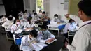 Sejumlah pelajar mengenakan masker beraktivitas di sebuah sekolah di Phnom Penh (28/1/2020). Penyebaran virus corona pertama kali dilaporkan berasal dari kota Wuhan di China tengah. Hingga saat ini tercatat lebih dari 106 orang dan 4.000 telah terinfeksi virus corona. (TANG CHHIN SOTHY/AFP)