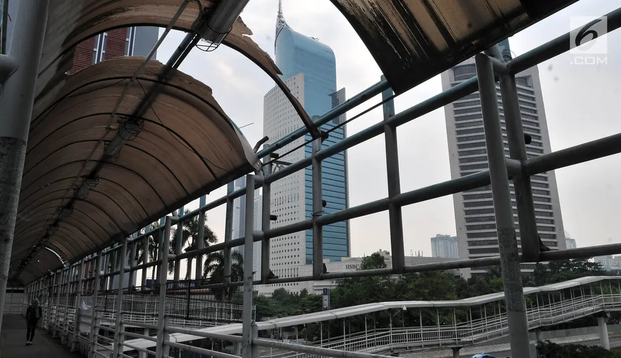 Pemandangan jembatan penyeberangan orang (JPO) yang berada di Jalan Sudirman, Jakarta, Rabu (17/4). Atap JPO yang yang rusak mengganggu pejalan kaki ketika hujan turun. (Merdeka.com/Iqbal Nugroho)