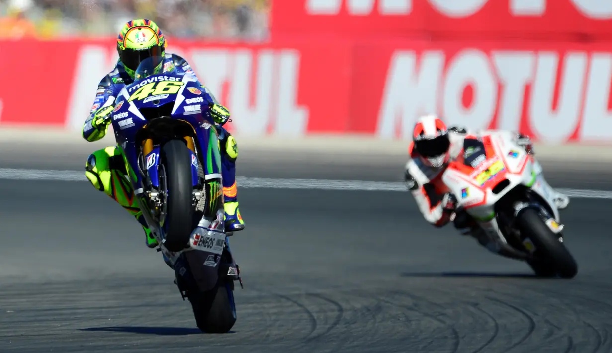 Pebalap Movistar Yamaha, Valentino Rossi, mengangkat ban depan motornya saat kualifikasi MotoGP Valencia di Sirkuit Ricardo Tormo, Valencia, Spanyol, (7/11/2015) (AFP Photo/Jose Jordan)