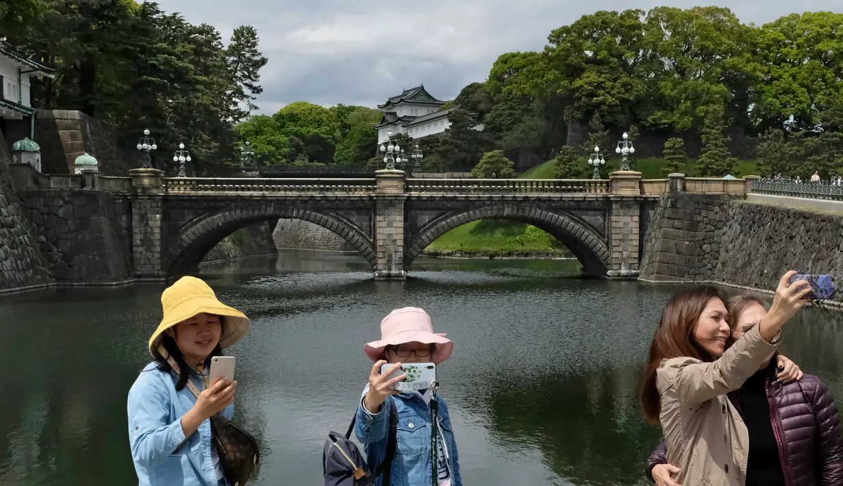 Wisatawan berswafoto dan selfie di pintu masuk utama Istana Kekaisaran di Tokyo, Jepang (29/4/2019). Kaisar Jepang Akihito akan turun dari Tahta Krisan pada 30 April 2019 mengakhiri 30 tahun masa pemerintahannya. (Kazuhiro NOGI / AFP)