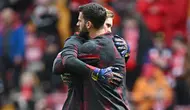 Kiper Liverpool, Alisson Becker (kanan) memeluk rekannya, Caoimhin Kelleher di sela sesi pemanasan jelang menghadapi Crystal Palace pada laga pekan ke-33 Premier League 2023/2024 di Anfield Stadium, Liverpool, Minggu (14/4/2024). (AFP/Paul Ellis)