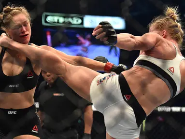 Tendangan dari Holly Holm, mendarat di kepala Ronda Rousey, perebutan gelar juara kelas bantam UFC Women di Stadion Etihad, Melbourne, Minggu (15/11/2015). Rousey, kalah KO dari Holm. (AFP Photo/Paul Crock)