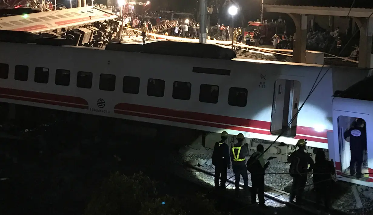 Petugas penyelamat berkumpul di lokasi tergelincirnya kereta Puyuma Express di Yilan, Taiwan, Minggu (21/10). Kantor Berita Pusat Taiwan melaporkan bahwa lusinan orang mungkin masih terperangkap di dalam gerbong kereta. (AP Photo/Johnson Lai)