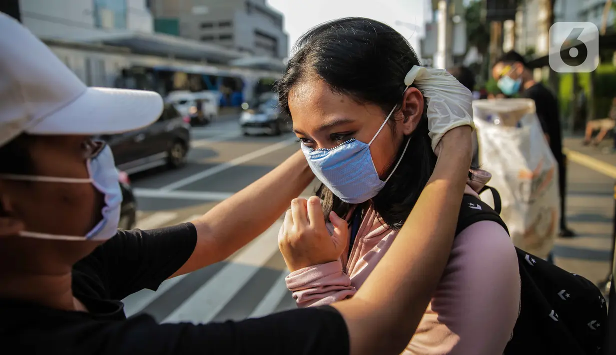 Relawan membagikan masker kepada pejalan kaki di kawasan Bundaran HI, Jakarta, Selasa (17/3/2020). Sebanyak 3.000 masker dibagikan secara gratis sebagai salah satu bentuk keprihatinan sekaligus berpartisipasi dalam upaya mencegah penyebaran virus corona COVID-19. (Liputan6.com/Faizal Fanani)